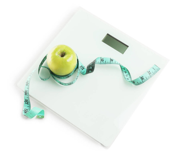Weight scales with measuring tape and apple on white background. Slimming concept - Φωτογραφία, εικόνα