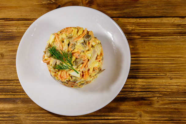 Lekkere salade met kipfilet, geroosterde champignons, wortelen, geraspte kaas, eieren en mayonaise op houten tafel. Bovenaanzicht - Foto, afbeelding