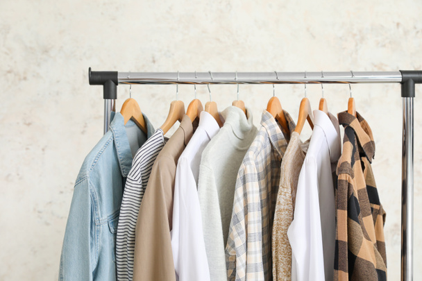 Rack with clothes on light background - 写真・画像