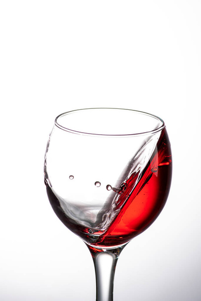 drop falling into a glass with red wine and a splash at an amazing angle - Foto, Imagem