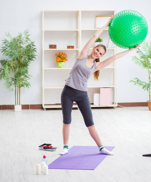 Νεαρή γυναίκα άσκηση με μπάλα σταθερότητας στο γυμναστήριο - Φωτογραφία, εικόνα