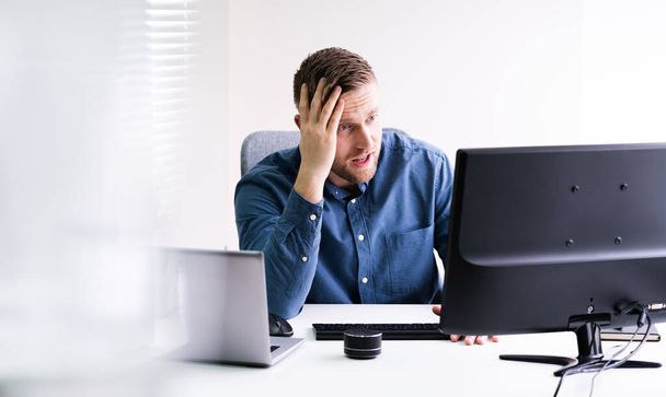 Stressed Young Businessman Sitting At Desk In Office - Photo, Image