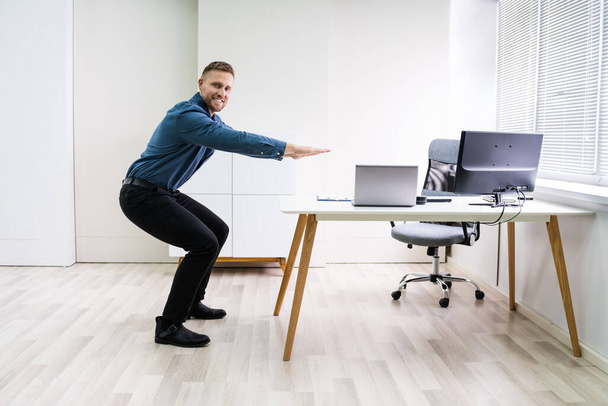Smiling Young Businessman Doing Sit-ups At Workplace - Фото, зображення