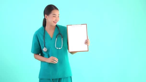 Muotokuva kaunis nuori aasialainen lääkäri nainen osoittaa tyhjä leikepöydälle sininen eristetty tausta
 - Materiaali, video