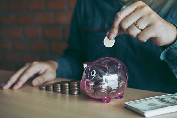 Men are holding coins dropping to the piggy bank with the concept of saving. - Photo, Image