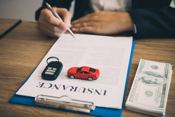 Agent unterschreibt den Versicherungsvertrag für das Auto am Dokument auf dem Schreibtisch. - Foto, Bild
