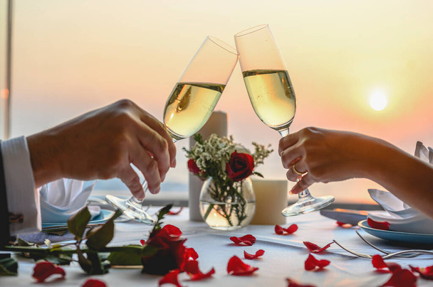 Couple enjoying of Cheers glass of wine  in a restaurant  at sunset. Valentine's, Couple, Honeymoon, Dinner, Wine, Romantic concept.  - Фото, изображение