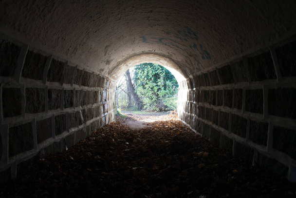 Tunnel met licht aan het eind, er is hoop aan het einde, stenen muurtunnel. donker in het begin - Foto, afbeelding