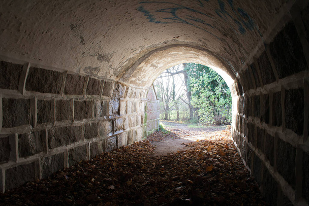 Тоннель со светом в конце, есть надежда в конце, каменная стена туннеля. темно в начале
 - Фото, изображение