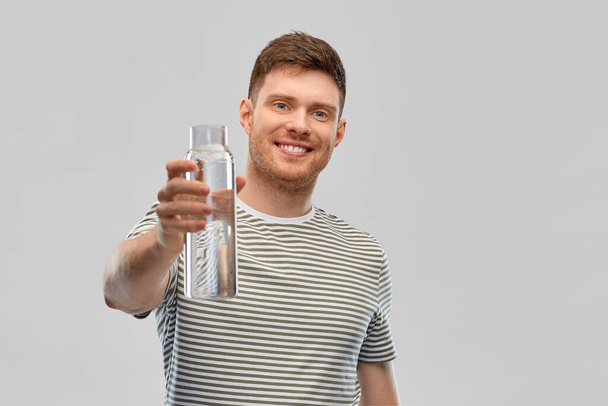 happy smiling man holding water in glass bottle - Photo, image