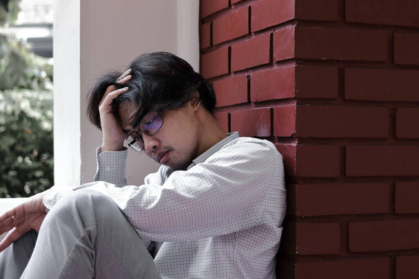 Väsynyt ylityöllistetty nuori Aasian liiketoiminnan manin masennus kädet otsa
 - Valokuva, kuva