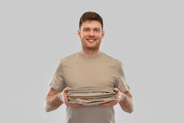smiling young man sorting paper waste - 写真・画像