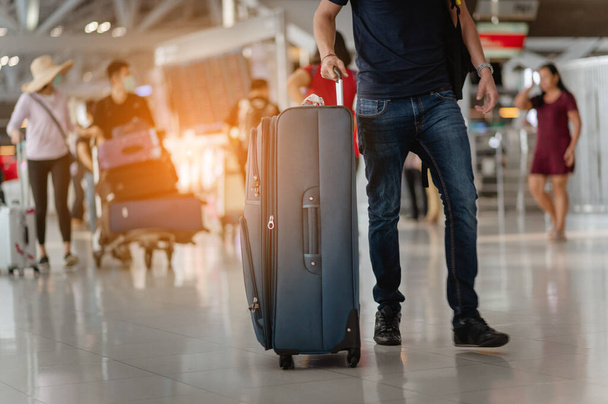 Travelers are walking to drag luggage in modern airport terminal to travel to new places. Rear view. Copy space. Luggage, traveler, travel, airport, walking, holiday concept. - 写真・画像