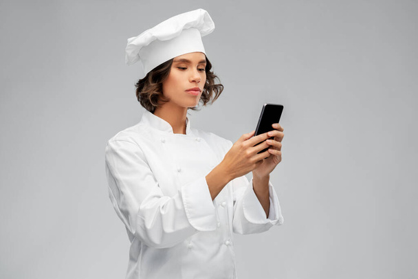 female chef in toque with smartphone - Фото, изображение