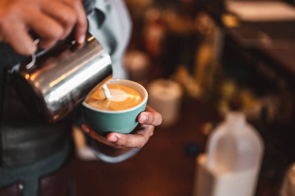 Close-up of professionally extracting coffee by barista with a pouring steamed milk into coffee cup making beautiful latte art. coffee, extraction, deep, cup, art, barista concept.  - Foto, afbeelding