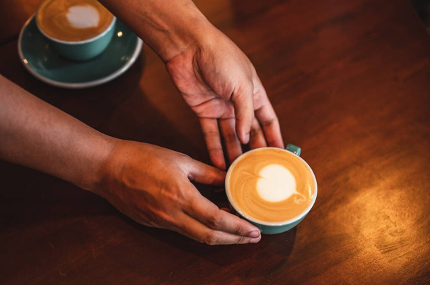 Close up of hands barista man serving coffee in coffee shop. male hands placing a cup of coffee on table. Coffee, Barista, extraction, serve, cafe, lifestyle concept. - Φωτογραφία, εικόνα