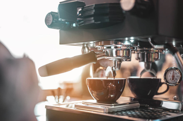 Close-up coffee maker that is professionally extracting coffee by barista with a deep white glass in the evening sun light. coffee, extraction, deep, machine, make, barista concept.  - Foto, afbeelding