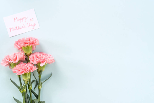 Den matek pozadí, karafiát parta - Krásné světle růžové kytice izolované na pastelově modrém stole, horní pohled, byt ležel, kopie prostor design. - Fotografie, Obrázek