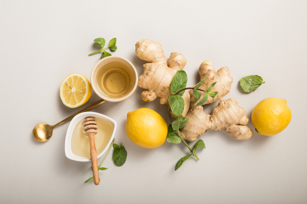 Ginger Lemon Tea with Honey. Warming immune boosting tea with citrus and ginger. Cup, honey,  ginger root on grey  pastel background, copy space, top view. - Φωτογραφία, εικόνα