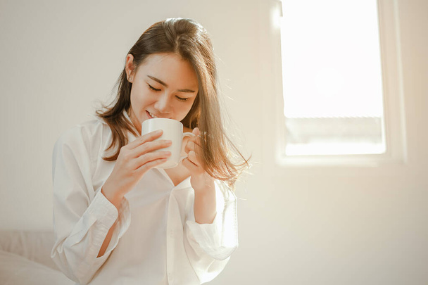 Young woman asia wake up refreshed in the morning and relaxing eat coffee, cornflakes, bread and apple for breakfast at house on holiday. Asian, asia, relax, breakfast, refresh, lifestyle concept. - Photo, image