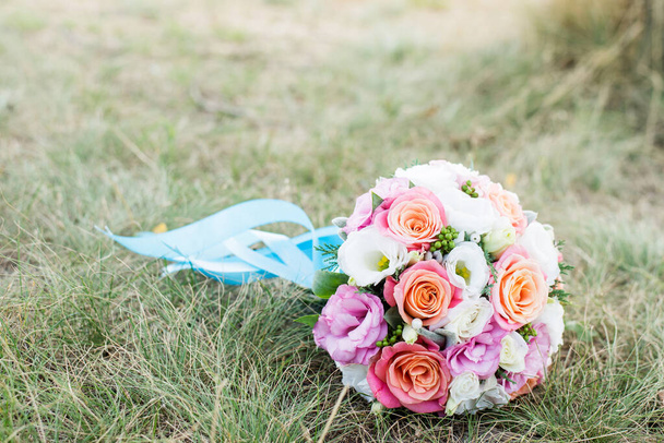 Hochzeitshintergrund. Der Brautstrauß mit rosa und weißen Blumen auf dem Gras. Liebeserklärung. Hochzeitskarte, Details zum Tag - Foto, Bild