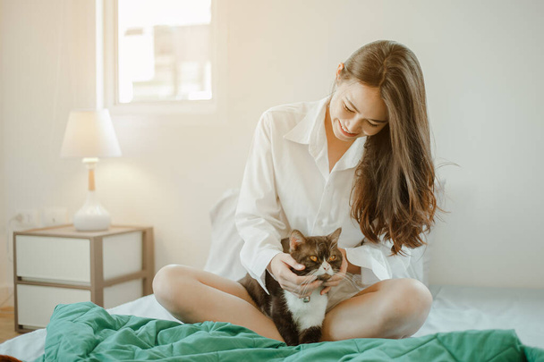Young woman asia wake up refreshed in the morning playing with cats at bed happily on holiday. Asian, asia, relax, happiness, refresh, lifestyle concept. - Fotografie, Obrázek