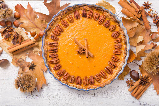Pumpkin Pie with pecan nut and cinnamon on rustic background, top view, copy space. Homemade autumn pastry for Thanksgiving - Photo, image