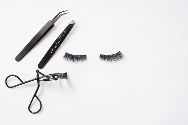 False lashes and black tweezers, isolated on white background,copy space - Φωτογραφία, εικόνα