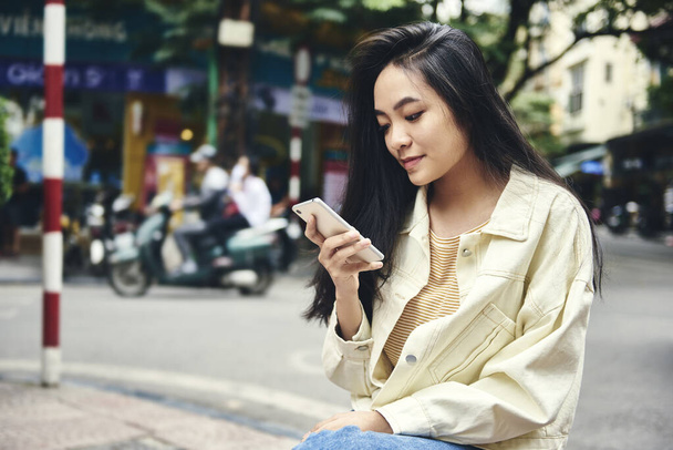 Вьетнамская женщина использует смартфон на улице
 - Фото, изображение
