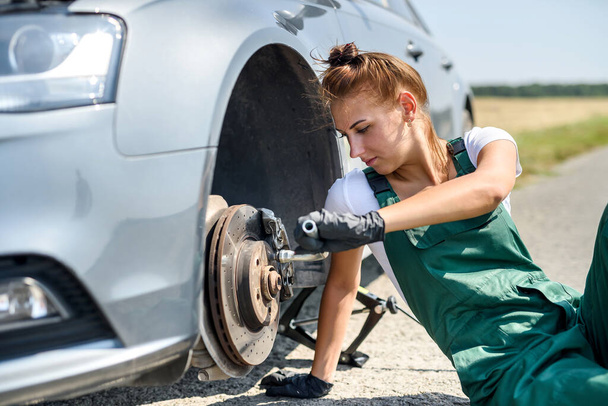 Женщина в форме работает на техобслуживание автомобильных тормозов. Ремонт машин. Безопасность - Фото, изображение