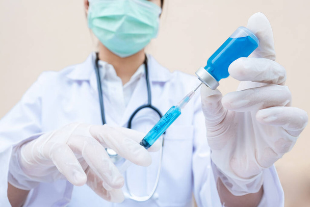 De hand van de arts houdt een blauwe vaccinbuis en spuit vast.. - Foto, afbeelding