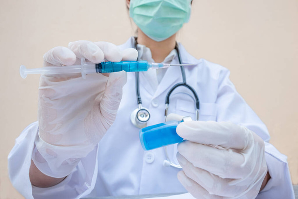 Рука лікаря тримає синю вакцину і шприц
. - Фото, зображення