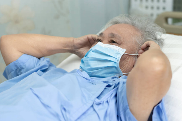 Asian senior or elderly old lady woman patient wearing a face mask in hospital for protect safety infection and kill Novel Coronavirus (2019-nCoV) Covid-19 virus. - Foto, afbeelding