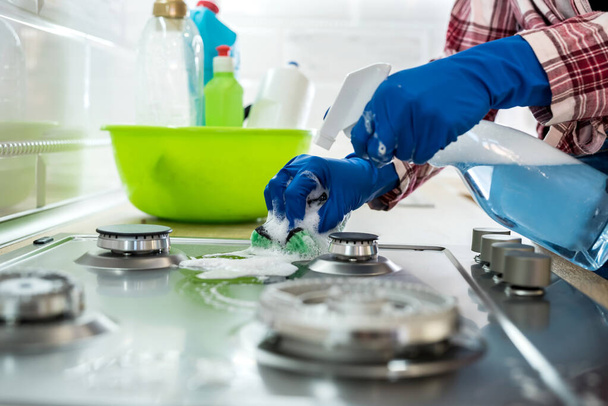 young woman cleaning in rubber gloves and sponge in the kitchen at home. - Foto, Bild