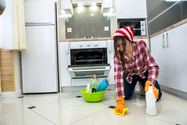 nainen kumihanskat ja desinfiointiaine pesee lattian keittiössä. - Valokuva, kuva