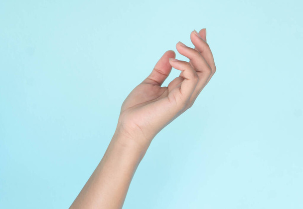 Γυναίκα χέρια κρατώντας κάτι σε μπλε φόντο για την έννοια της διαφήμισης του προϊόντος - Φωτογραφία, εικόνα