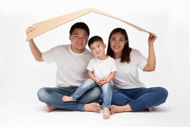 Aziatische familie glimlachen en spelen huis door bruin papier op geïsoleerde witte achtergrond. Nieuw thuis jong familie concept - Foto, afbeelding