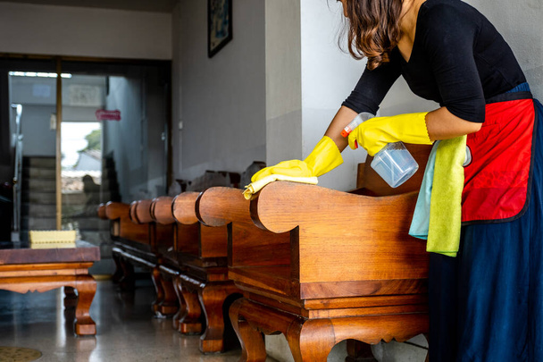 De huishoudsters gebruikten doek en reinigingsoplossing om tafel en stoel schoon te maken. - Foto, afbeelding