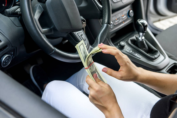Vrouwelijke handen bieden dolar bundel. Vrouwelijke chauffeur geeft steekpenningen - Foto, afbeelding