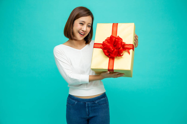 Gelukkige mooie Aziatische vrouw glimlach met gouden geschenkdoos geïsoleerd op groene achtergrond. Tienermeisjes verliefd, cadeautjes ontvangen van geliefden. Nieuwjaar of kerstconcept - Foto, afbeelding