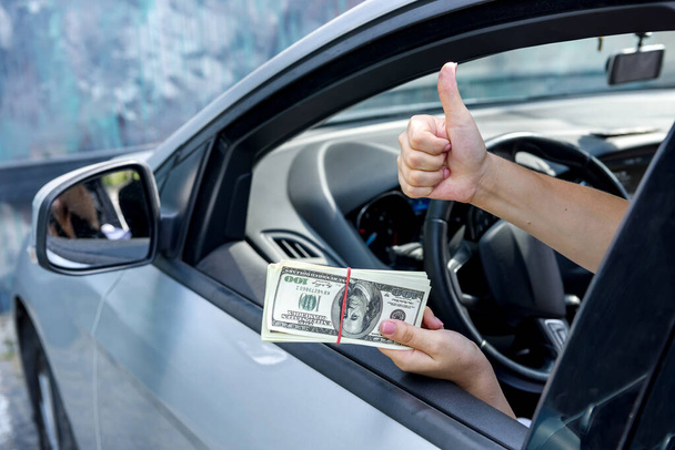 Bribe concept. Female hands giving dollar bundle inside car close up - Photo, Image
