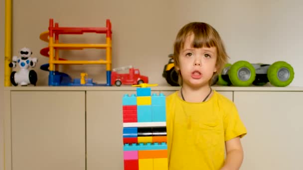 Leuke jongen demonstreert een toren speelgoed gemaakt van kubussen - Video