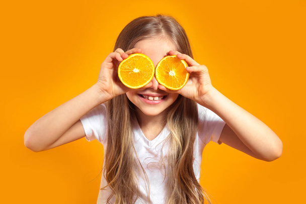 Funny little girl with citrus fruit on yellow background - Foto, imagen