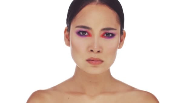 A displeased half naked asian woman with bright fashion eye makeup is getting angry standing isolated over white background in studio - Séquence, vidéo