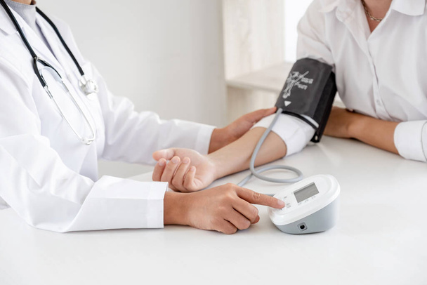 El médico evalúa al paciente con un estetoscopio, un monitor de presión arterial y registra los resultados. - Foto, imagen