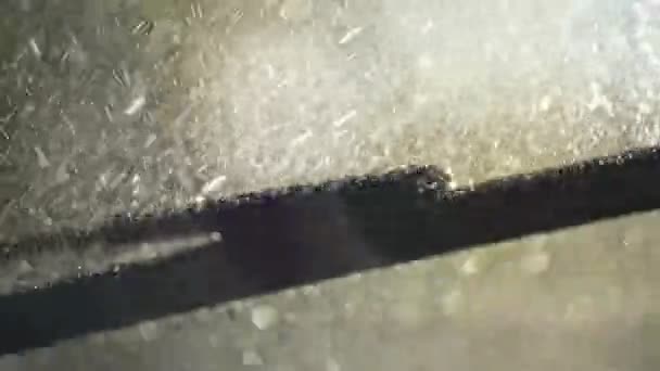 Washing the car windshield with liquid and car wipers. Many small splashes cover the glass surface. Slow motion shot - Footage, Video
