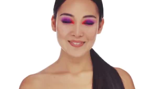 A smiling young half-naked woman with bright fashion eye makeup is showing an ok gesture to the camera isolated over white background - Felvétel, videó
