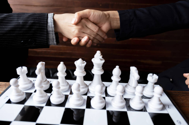 Geschäftsfrauen beim Händeschütteln vor dem Schachspiel an Bord mit weißem Hintergrund, fordern die Planung der Geschäftsstrategie zum Erfolgskonzept heraus. - Foto, Bild