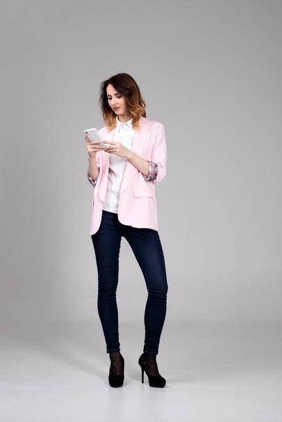 девушка в розовой куртке и белой рубашке разговаривает по телефону - Фото, изображение