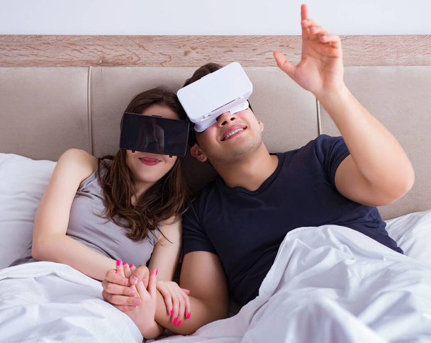Wife and husband with virtual reality goggles in the bed - Foto, imagen